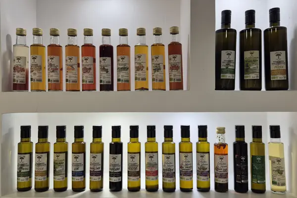 alt="Gamme de bouteilles d'huiles végétales artisanales alignées sur une étagère éclairée"